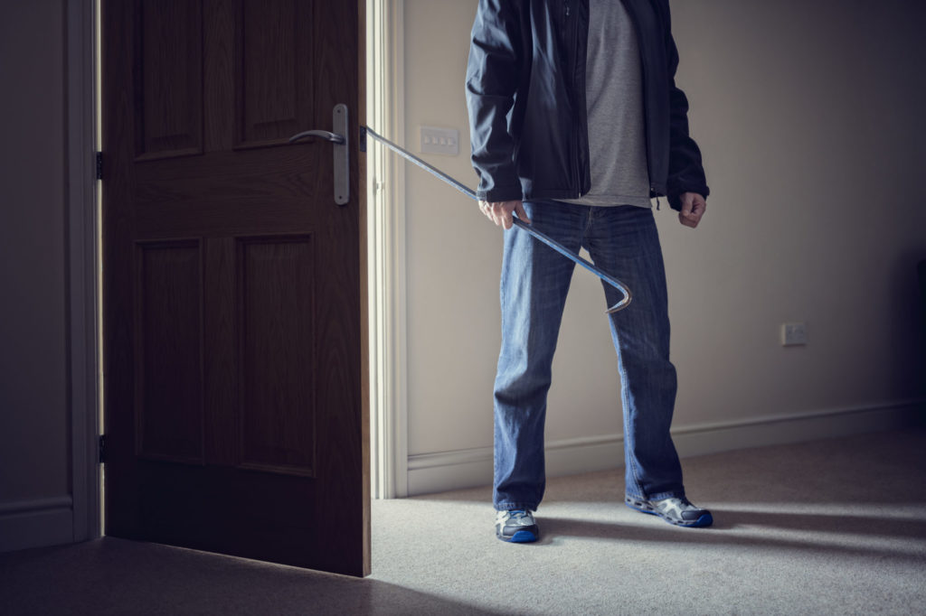 Burglar committing a burglary crime in a house with a crowbar
