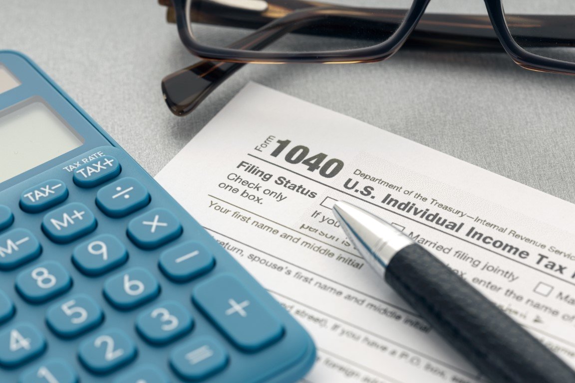 Tax concept. Tax form, calculator, eyeglasses and pen on table